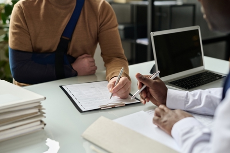 An injured worker meeting with a workers' compensation attorney at a desk while reviewing claim documents.